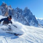 Snowboardeur descendant une pente abrupte avec un paysage montagneux enneigé en arrière-plan