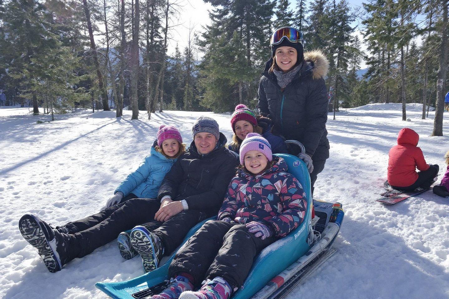 Famille en tenue d'hiver profitant d'une journ&eacute;e de neige dans la for&ecirc;t