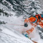 Un skieur en tenue orange plonge dans une neige fraîchement tombée.