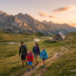 Famille en randonnée marchant sur un sentier montagneux vers un refuge au coucher du soleil dans les Pyrénées.