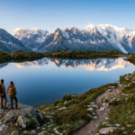 Accéder au Lac Blanc à Chamonix : évitez la foule Deux randonneurs admirant le reflet du massif du Mont-Blanc dans les eaux calmes du Lac Blanc à Chamonix.