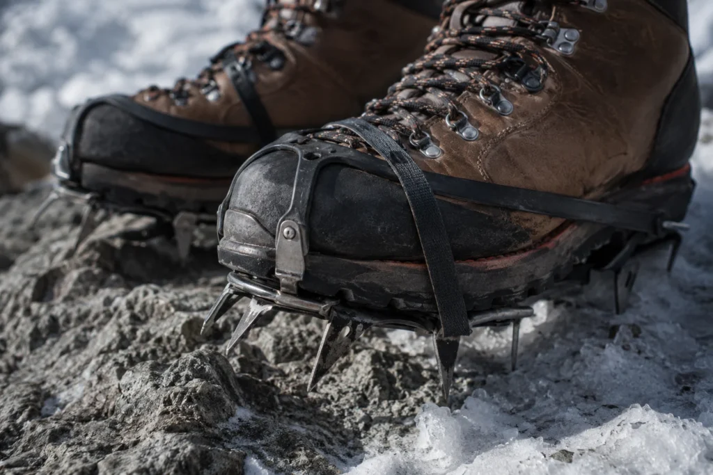 Gros plan sur des chaussures d'alpinisme équipées de crampons sur terrain rocheux